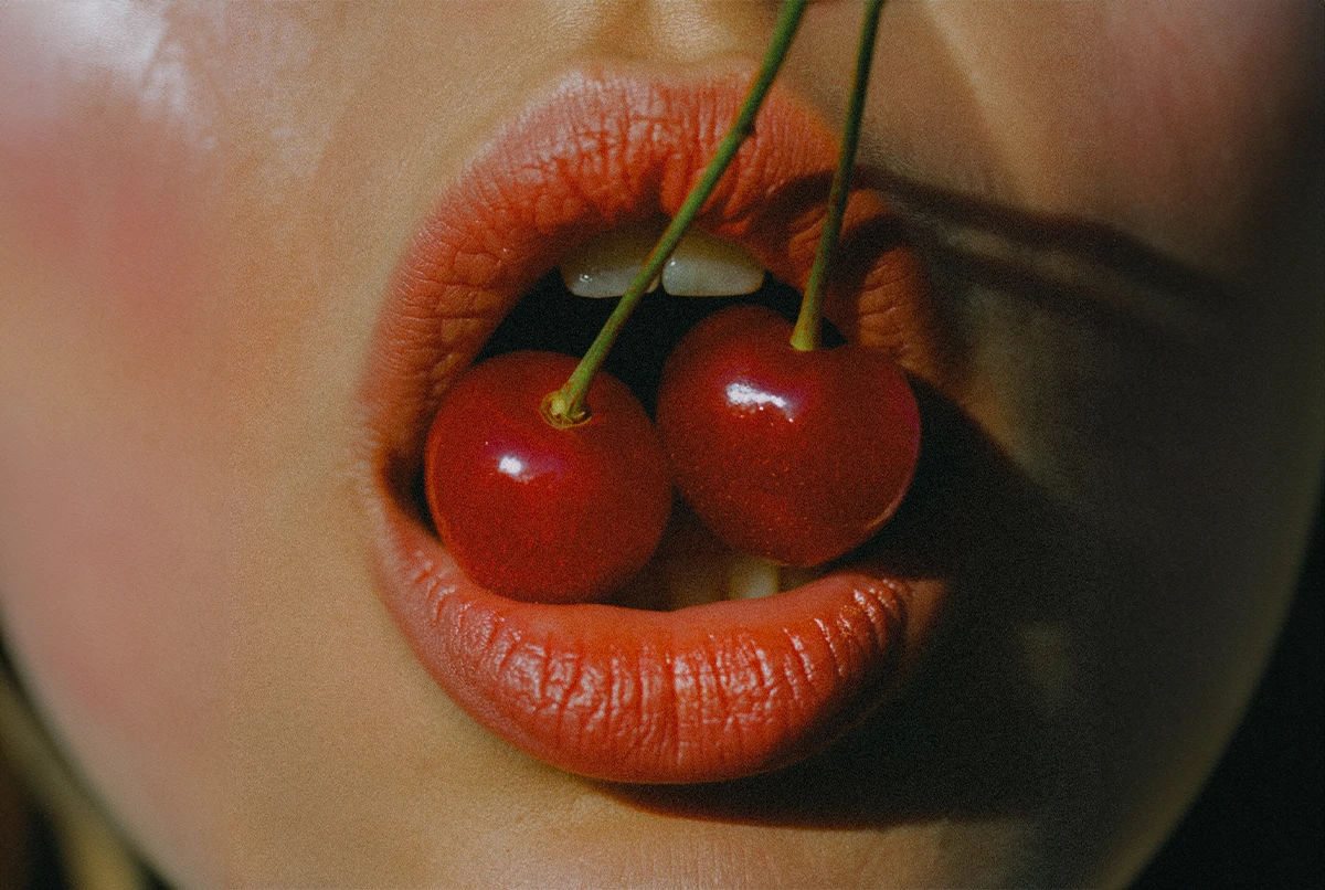 Close-up of lips holding two cherries between them