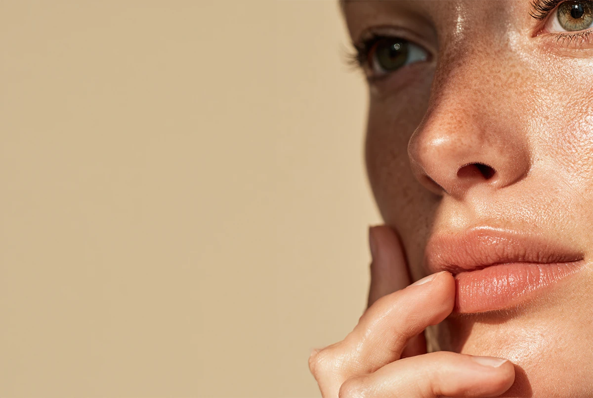 Close-up of a person's face with a thoughtful expression, resting hand by lips