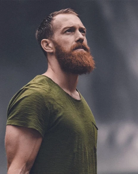 Man with a beard and short hair wearing a green shirt, looking upwards