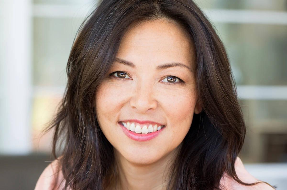 Close-up of a woman with long dark hair smiling at the camera