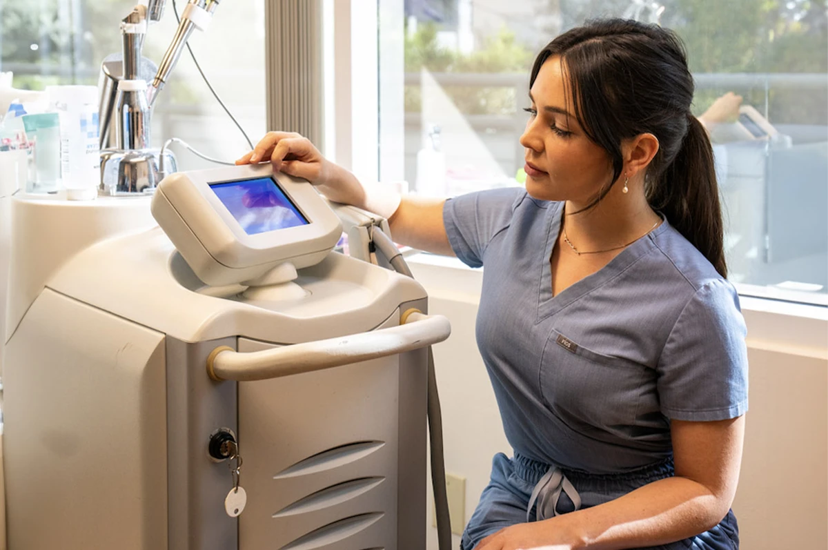 A person in scrubs operates a medical device in a clinical setting