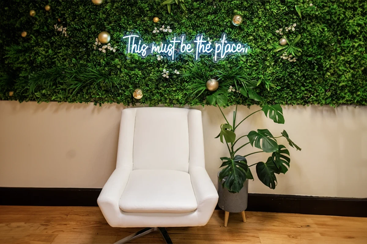 White chair in front of a green wall with a neon sign that says 
