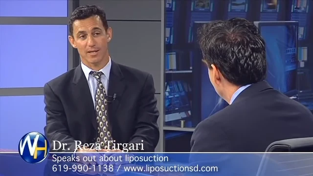 Two men in suits are engaged in a conversation on a television set