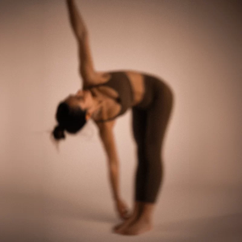 A person stretches to one side while standing barefoot on a plain background